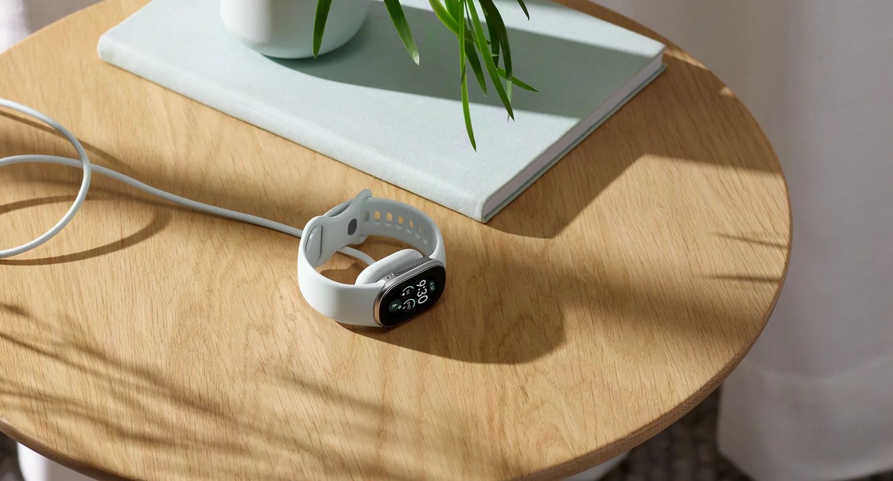 Fitbit Edge na magnetické nabíječce na stolku