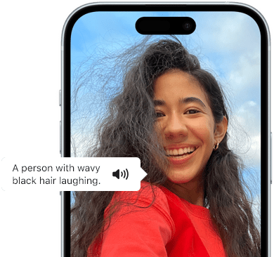 iPhone 15 so zobrazeným oznámením funkcie VoiceOver, ktorá popisuje fotografiu: smejúca sa osoba s vlnitými čiernymi vlasmi
