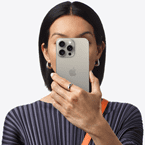 A person holds an iPhone 15 Pro Max in front of their face to conceal their identity