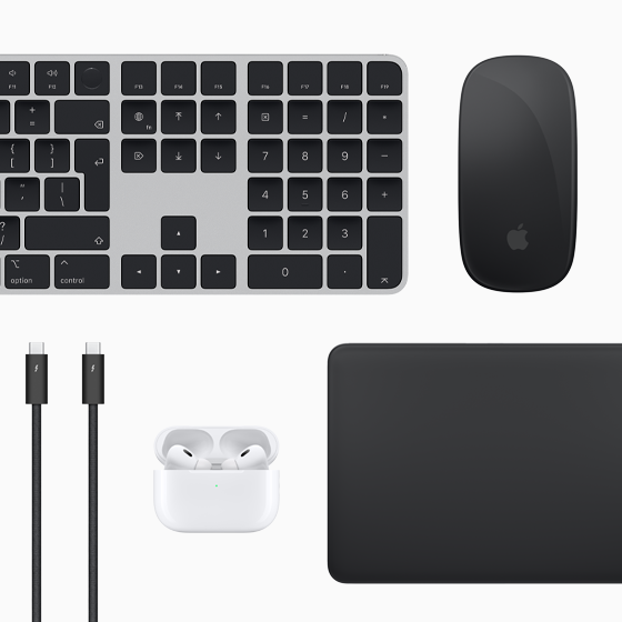 Pohľad zhora na doplnky k Macu: Magic Keyboard, Magic Mouse, Magic Trackpad, AirPods a Thunderbolt káble