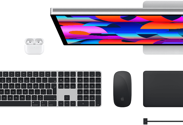 Pohled shora na doplňky k Macu: Studio Display, AirPods, Magic Keyboard, Magic Mouse a Magic Trackpad