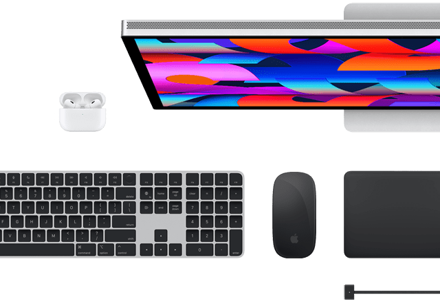 Pohľad zhora na vybrané doplnky k Macu: Studio Display, Magic Keyboard, Magic Mouse, Magic Trackpad, AirPods a MagSafe nabíjací kábel